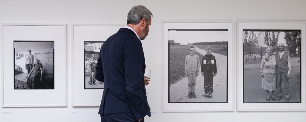 Ein Mann schaut sich vier Schwarz-Weiß-Fotografien an.