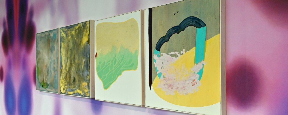 Vier abstrakte Gemälde hingen an einer Wand mit einem Muster aus Rot-, Violett- und Lila-Tönen.