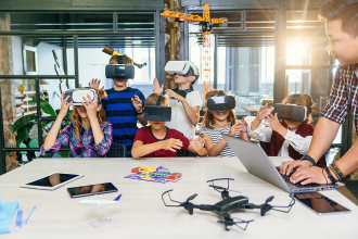 Eine Gruppe von glücklichen Grundschülern mit VR-Headset während des PRogrammierunterrichts.