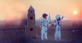 Zwei Kinder im Raumanzug stehen vor selbstgebastelter Rakete aus Pappe