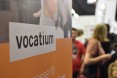 Logowand Vocatium mit Menschen auf dem Messebereich im Hintergrund