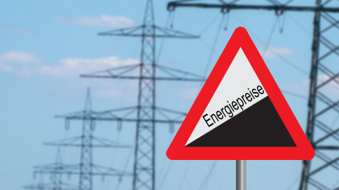 Warnschild mit Schriftzug Energiepresie vor Strommasten stehend