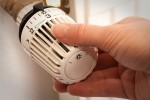 Frauenhand dreht an einem Heizungsthermostat